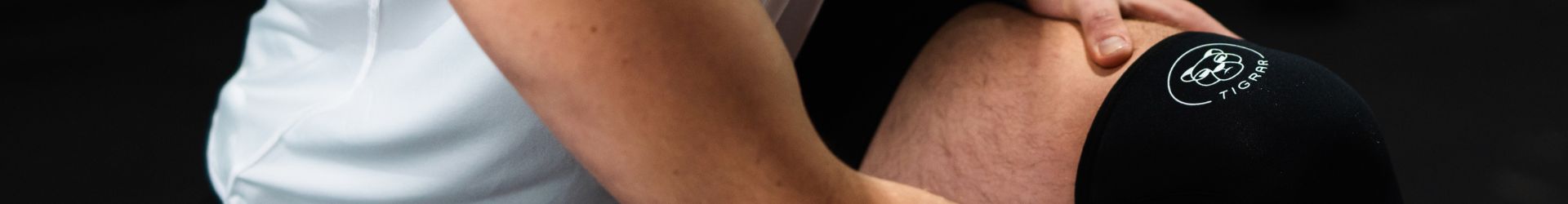 Atleet zit op 1 knee met 7mm knee sleeves om in de gym