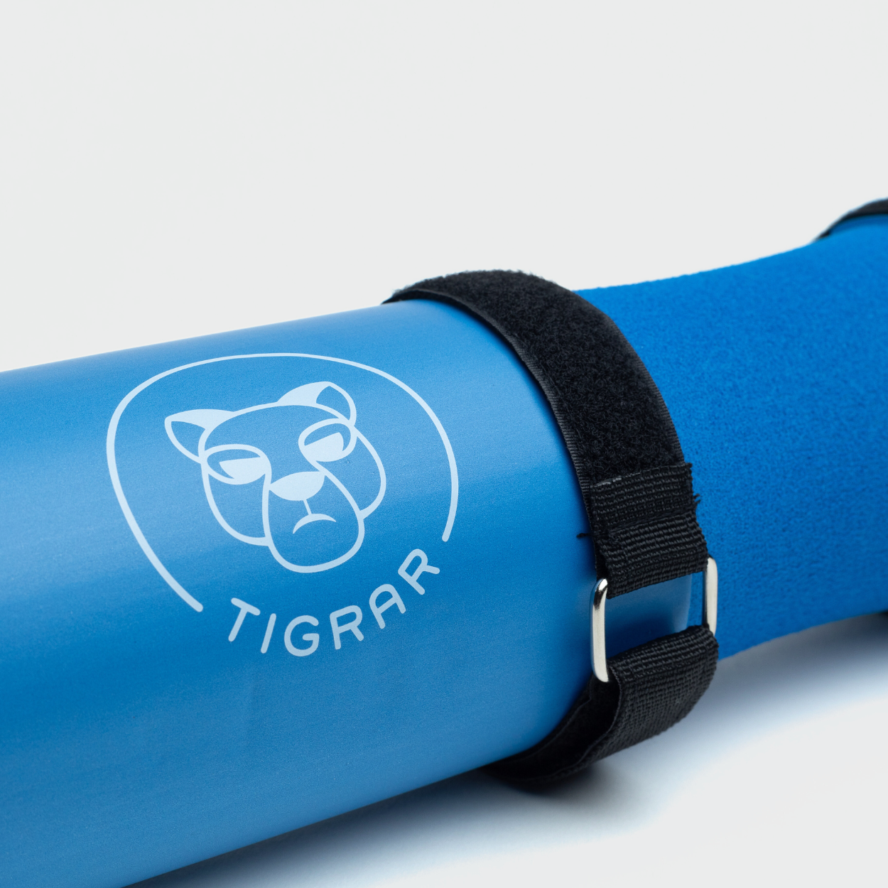 Close-up van een blauwe Tigrar gym barbell pad met klittenband strap, op een grijze achtergrond.