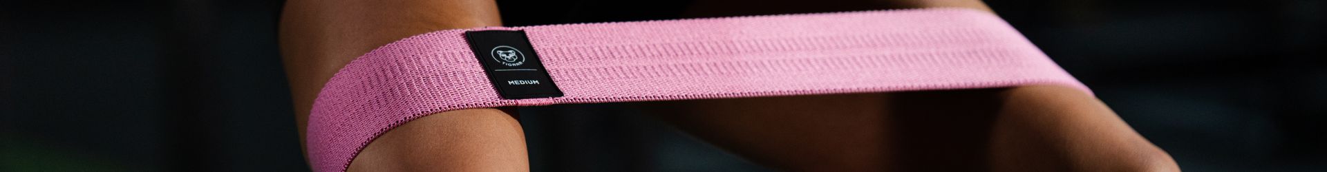 Vrouw doet een squat met roze booty band om haar bovenbenen, close up shot