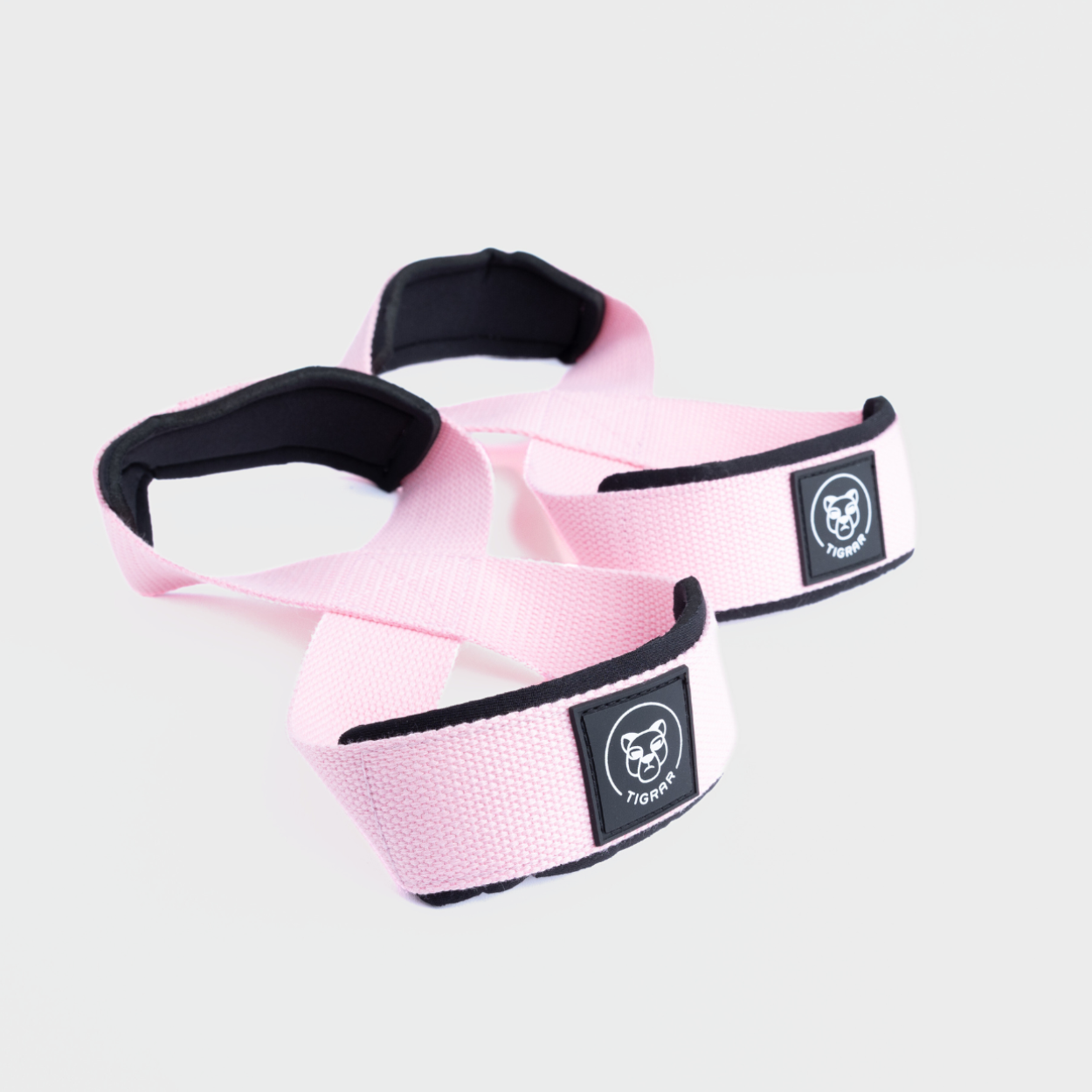 Roze Tigrar Figure 8 straps met dubbele neopreen padding, ideaal voor comfort tijdens het liften, tegen een grijze achtergrond.