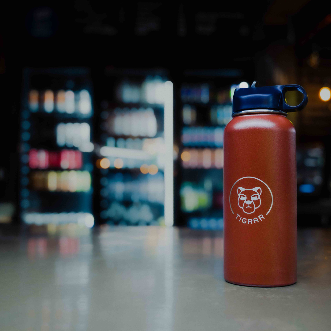 Elegant ontworpen rode Tigrar thermosfles op de bar van de sportschool, weerspiegelt de focus op gezondheid en hydratatie.