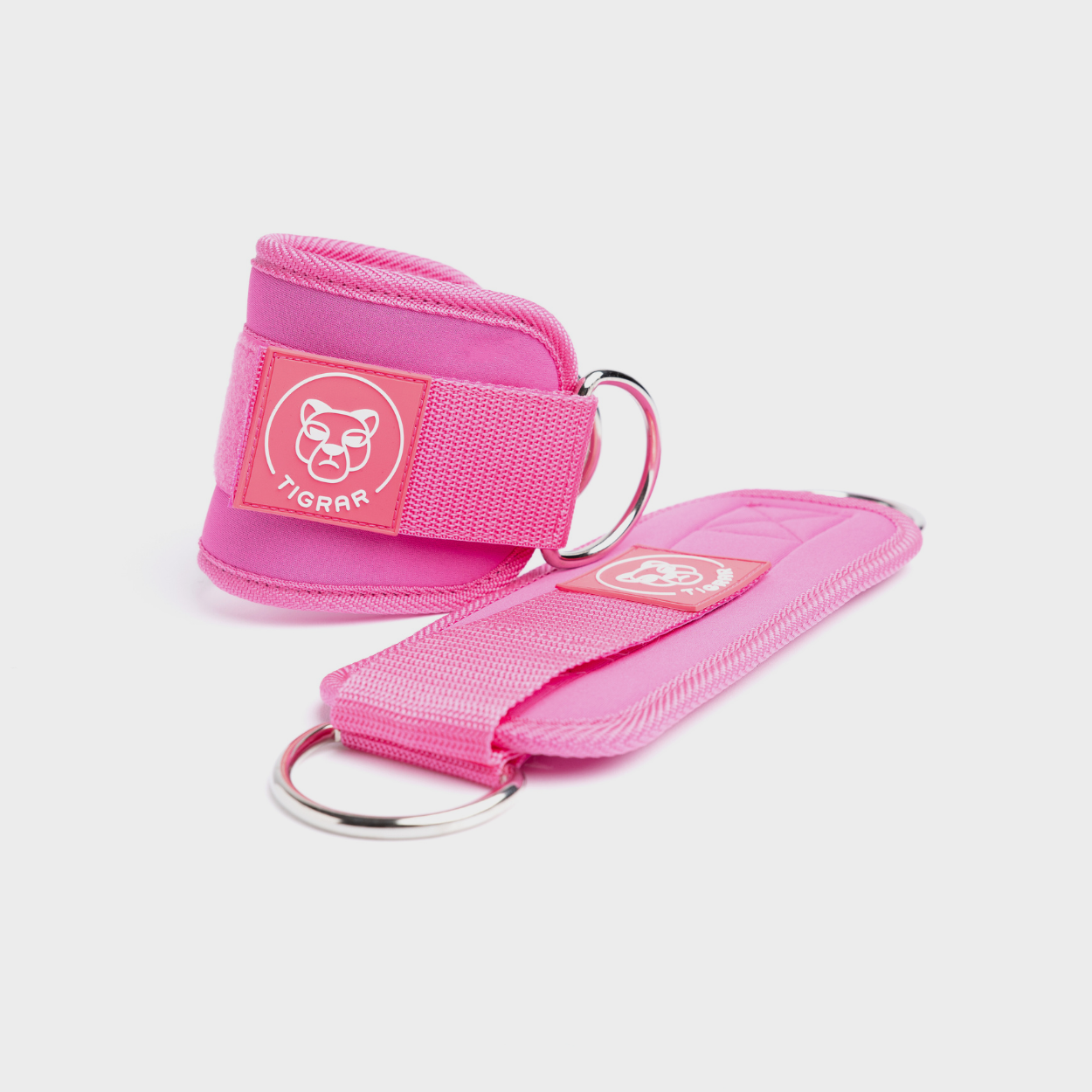 Roze Tigrar enkel straps gemaakt van duurzaam neopreen met stevige klittenbandsluiting. Ondersteunt de enkels tijdens trainingen en is ideaal voor weerstandsoefeningen zoals leg raises.
