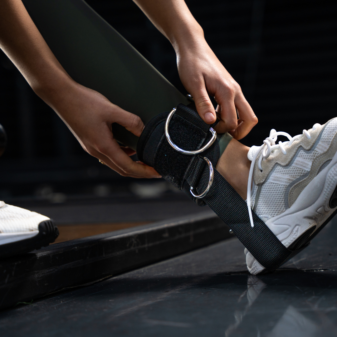 Close-up van een sportieve dame die een Tigrar enkel strap met zachte padding en kickback strap onder de hiel vasthoudt.