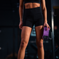Sportieve jonge dame staat met een paarse weerstandsband in haar hand klaar voor haar workout