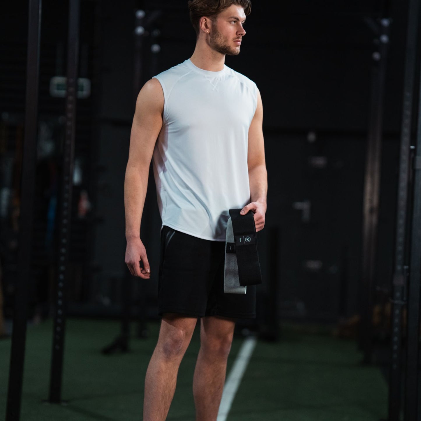 Sportieve man houdt een glute band set van Tigrar vast, klaar voor een krachttraining in de sportschool.