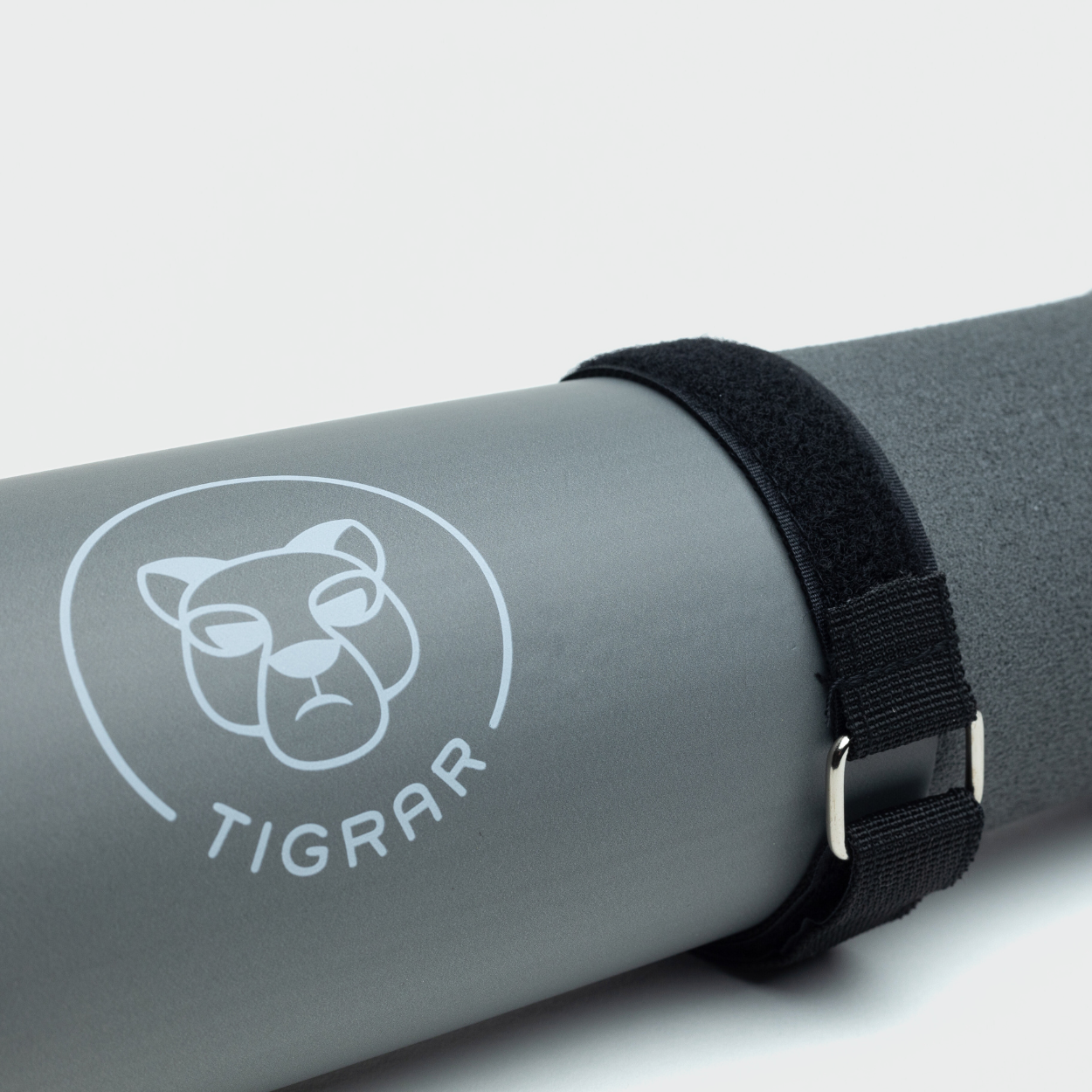 Gedetailleerde close-up van een grijze Tigrar bar pad voor hip thrusts, inclusief klittenband strap tegen een grijze achtergrond.