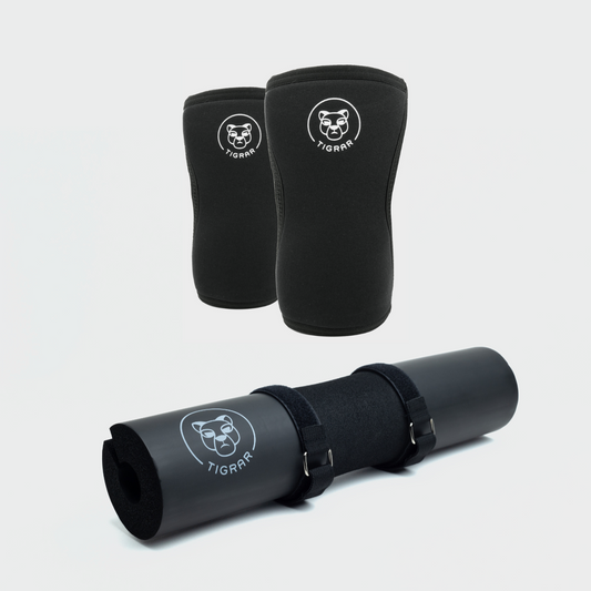 Zwarte knee sleeves naast een zwarte barbell pad. Essentiële Tigrar accessoires voor krachttraining en squat oefeningen.