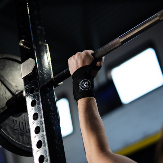 Close-up van bench press oefening met focus op één pols, waarbij de Tigrar wrist wrap duidelijk zichtbaar is voor extra ondersteuning.