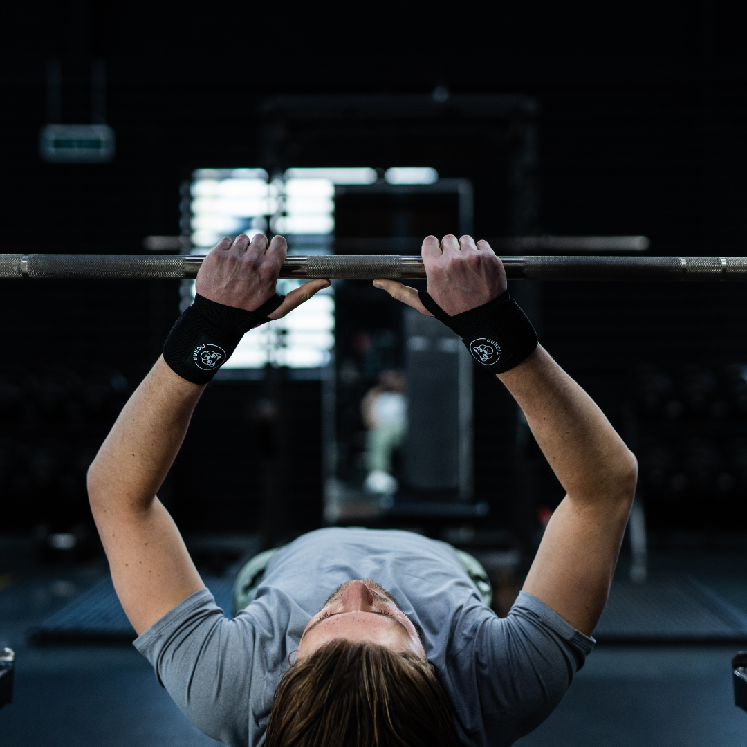 Atleet gebruikt nylon Tigrar wrist wraps voor ondersteuning tijdens bench press oefening.