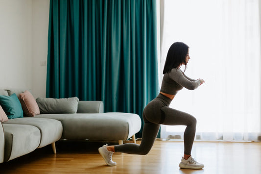 Sportieve jonge dame traint haar billen thuis door het uitvoeren van lunges