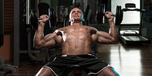 Gespierde man voert een incline dumbbell bench press uit in de gym. Focus op borstspieren trainen met dumbbells voor kracht en spiermassa.