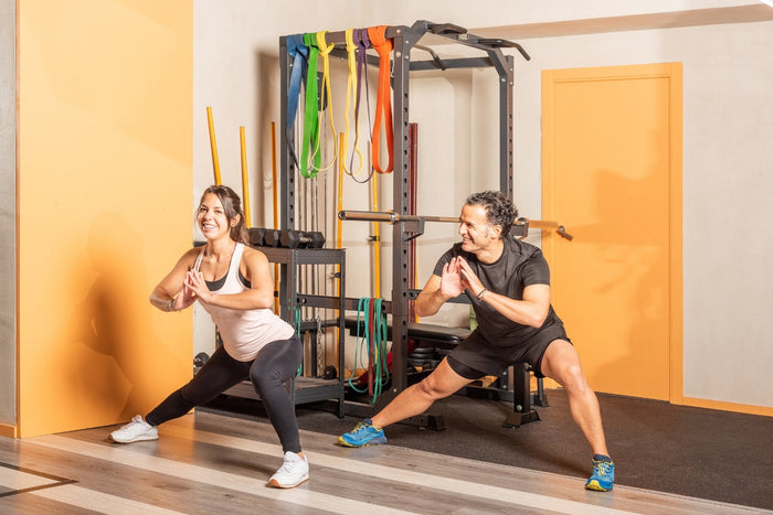 man en vrouw doen side lunges in een sportzaal