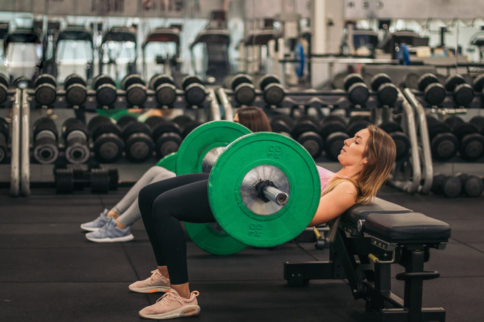 Vrouw voert barbell hip thrust uit in de gym, zijaanzicht van correcte houding.