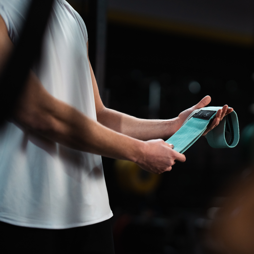 Atleet toont mint gekleurde Tigrar weerstandsband in de gym.