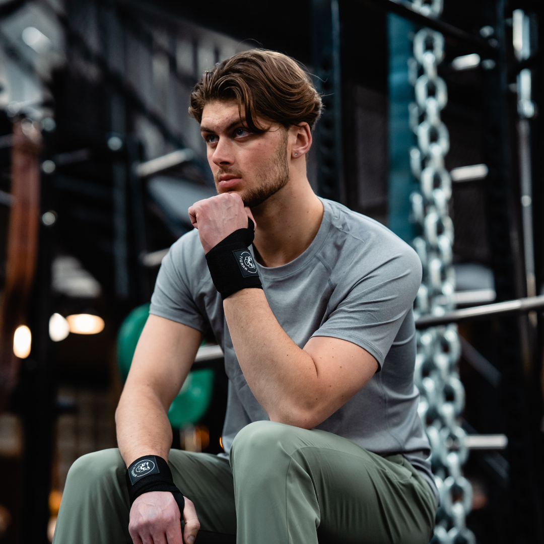 Atleet neemt rustmoment voor het bankdrukken, uitgerust met Tigrar wrist wraps, klaar voor de volgende set.