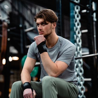 Atleet neemt rustmoment voor het bankdrukken, uitgerust met Tigrar wrist wraps, klaar voor de volgende set.