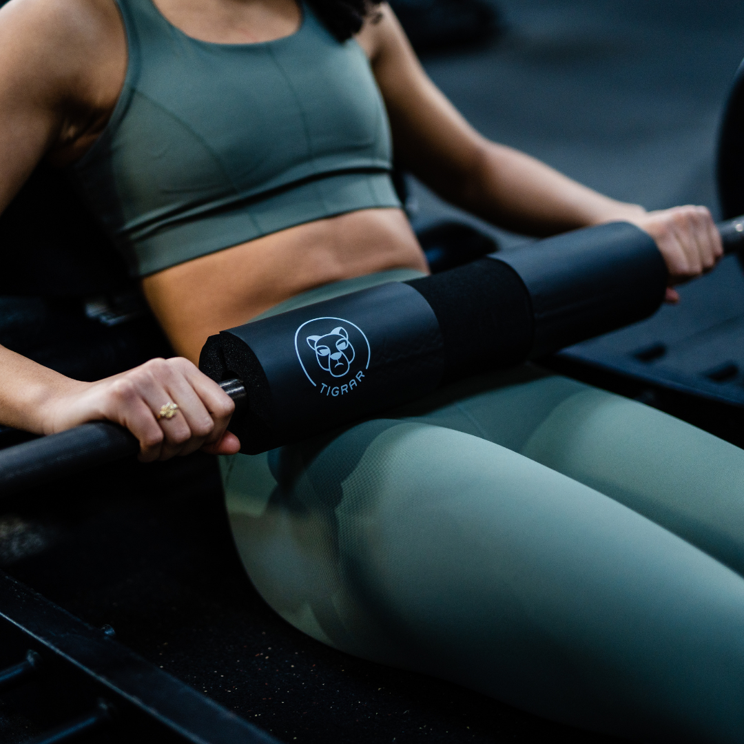 Close-up van een vrouw die een hip thrust doet met een barbell hip thrust pad op haar heupen.