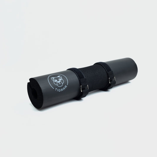 Zwarte Tigrar barbell pad voor hip thrusts, bevestigd met klittenband, tegen grijze achtergrond