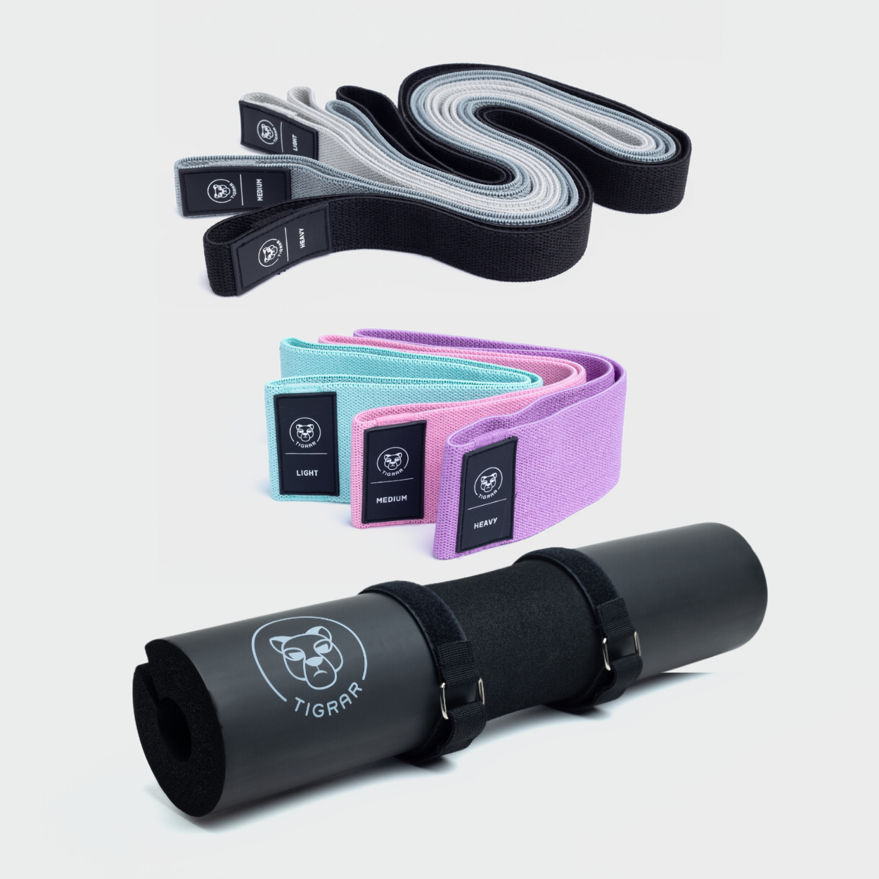 Set van Tigrar: drie lange weerstandsbanden in zwart, grijs, lichtgrijs, drie korte in mint, roze, paars en een zwarte barbell pad. Alle accessoires op een grijze achtergrond