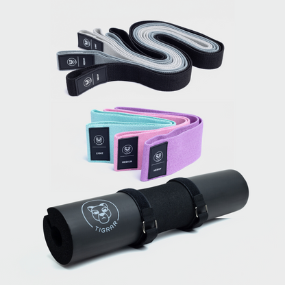 Set van Tigrar: drie lange weerstandsbanden in zwart, grijs, lichtgrijs, drie korte in mint, roze, paars en een zwarte barbell pad. Alle accessoires op een grijze achtergrond