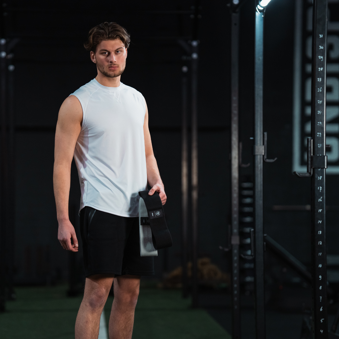 Atleet in de gym met een zwarte Tigrar resistance band in hand, klaar voor zijn training.